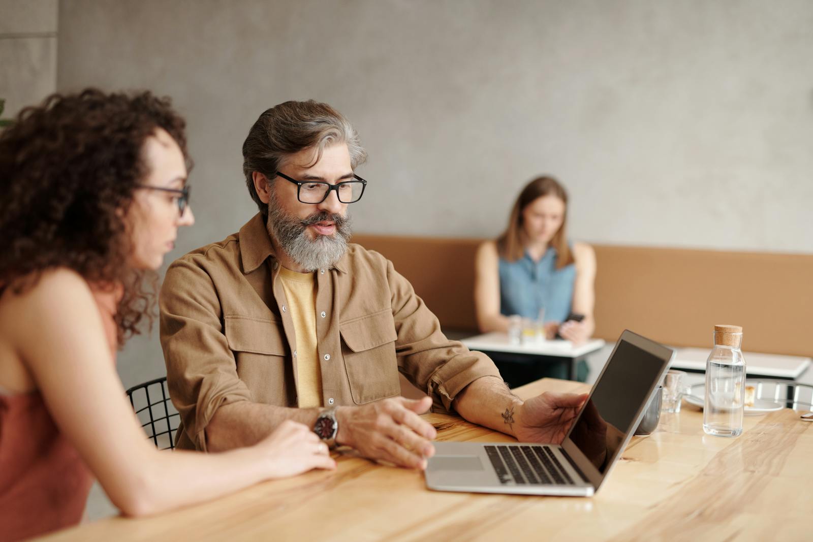 Business colleagues discussing operational details across a laptop